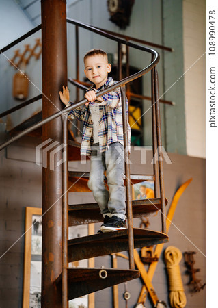 Funny little boy in plaid shirt and jeans in the interior of a country house. Funny little boy in plaid shirt and jeans in the interior of a country house. 108990478