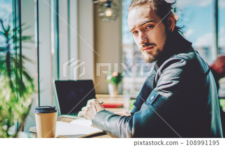 hipster student with studying indoors sitting at coffee shop with textbook for education 108991195