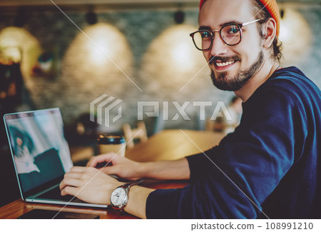 positive cheerful hipster blogger sitting on publicity area with modern laptop computer 108991210