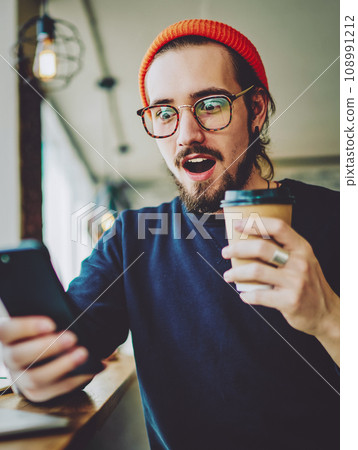 Amazed hipster guy watching shocking content news via application on cellphone and feeling wonder 108991212