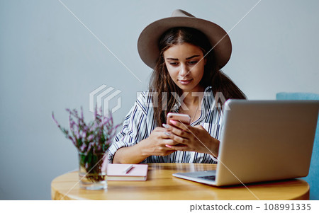 Young caucasian female blogger share multimedia files in social networks using mobile phone indoors Young caucasian female blogger share multimedia files in social networks using mobile phone indoors 108991335