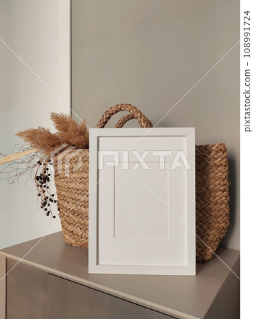 Empty photo frame mockup on wooden table. Elegant workspace, home office concept. Scandinavian minimalistic interior design. Copy space for artwork, photo or print presentation. 108991724