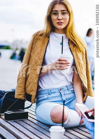 hipster girls resting together with beverage and communicating on summer free time hipster girls resting together with beverage and communicating on summer free time 108992188