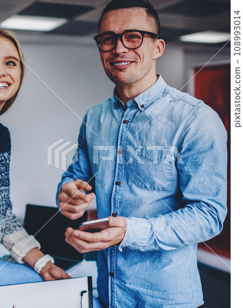 Positive young colleagues dressed in casual wear laughing during working process in office interior Positive young colleagues dressed in casual wear laughing during working process in office interior 108993014
