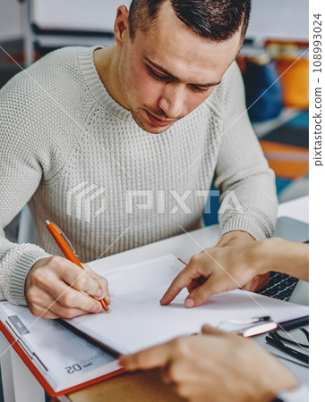 Pensive young man writing notes of plan during working process Pensive young man writing notes of plan during working process 108993024