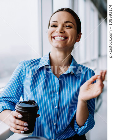 cheerful attractive female manager holding coffee cup and smiling enjoying career 108993174