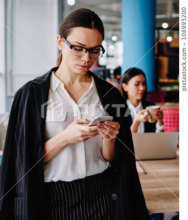 confident female read text message on cellular standing in office 108993200
