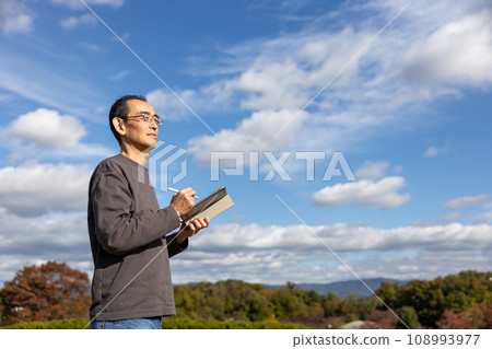 Mature man standing outdoors with a tablet 108993977
