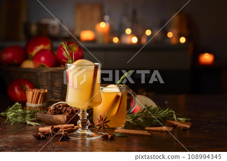 Mulled cider with apples, cinnamon, rosemary, and anise on a background of burning candles. 108994345