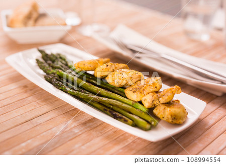 Fried chicken breast pieces with asparagus on white plate 108994554