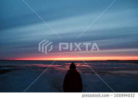Silhouette of a man against the sunset colorful sky at sunset at the sea. Gradient color. Sky texture. Beautiful abstract nature sunset as background. Silhouette of a man against the sunset colorful sky at sunset at the sea. Gradient color. Sky texture. Beautiful abstract nature sunset as background. 108994832