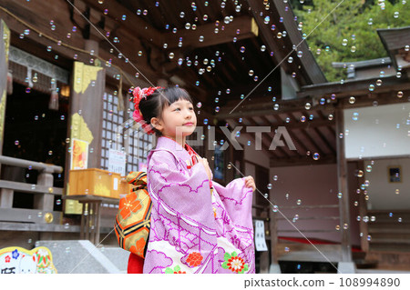 A cute girl wearing a long-sleeved kimono wearing a long-sleeved kimono for a 7-year-old's Shichi-Go-San pilgrimage on location at a shrine. Classic hairstyle. 108994890