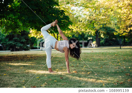 Young brunette asian woman practicing yoga during workout in park 108995139
