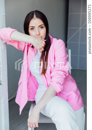 Beautiful brunette woman in white suit and pink jacket Beautiful brunette woman in white suit and pink jacket 108995271