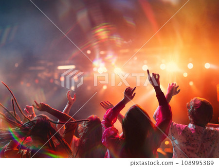 large group of people having fun, singing and dancing raising hands on concert of favorite artists in neon light, spotlights near stage large group of people having fun, singing and dancing raising hands on concert of favorite artists in neon light, spotlights near stage 108995389