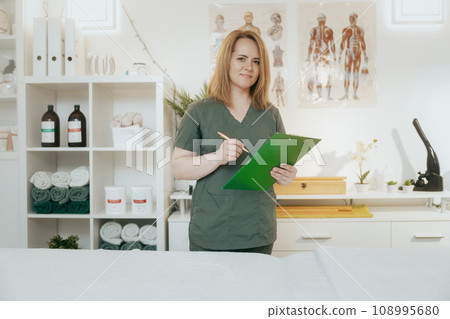happy female medical massage therapist in massage cabinet 108995680