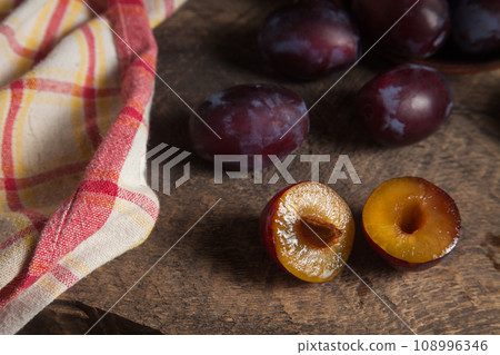 Whole and half of purple plums on wooden background. . Whole and half of purple plums on wooden background. . 108996346