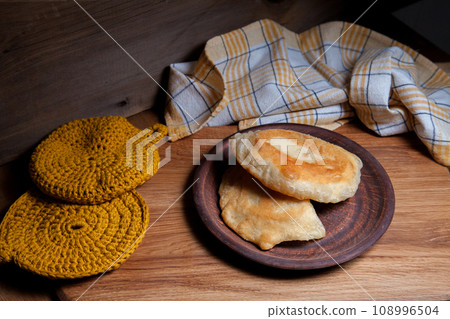Clay plate of fried meat pies on wooden table. Clay plate of fried meat pies on wooden table. 108996504