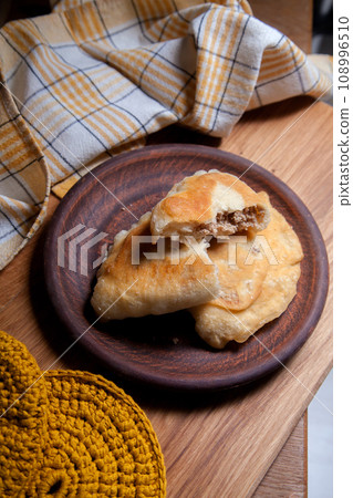 Clay plate of fried meat pies on wooden table. Clay plate of fried meat pies on wooden table. 108996510