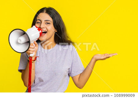 Indian woman talking with megaphone, proclaiming news loudly announcing advertisement discounts sale Indian woman talking with megaphone, proclaiming news loudly announcing advertisement discounts sale 108999009