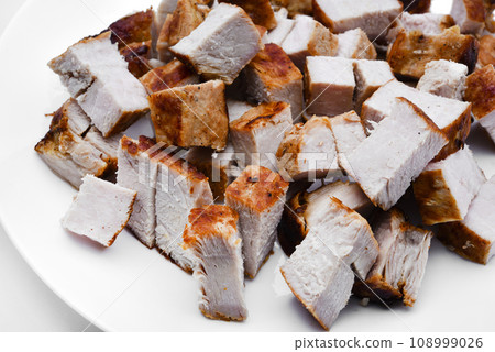 Pieces of fried pork meat on a white plate. Juicy and delicious pieces of barbecue meat. Pieces of fried pork meat on a white plate. Juicy and delicious pieces of barbecue meat. 108999026