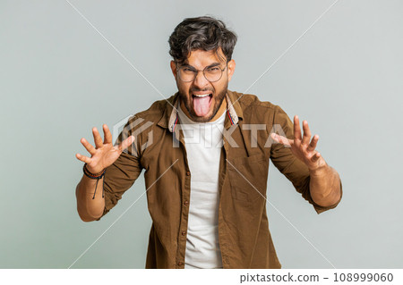 Cheerful funny bully Indian man showing tongue making silly faces, fooling around, joking, teasing Cheerful funny bully Indian man showing tongue making silly faces, fooling around, joking, teasing 108999060