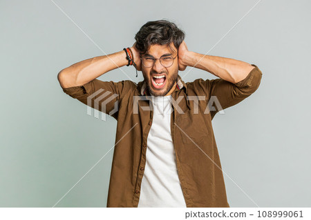 Annoyed irritated Indian man covering ears gesturing no avoiding advice ignoring noise loud voices Annoyed irritated Indian man covering ears gesturing no avoiding advice ignoring noise loud voices 108999061