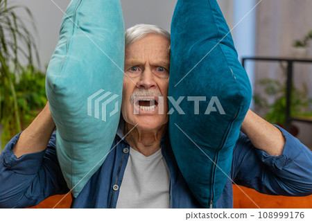 Neighbors repair work irritated man by loud music at home cover ears with pillows annoyed by noise 108999176