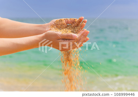 Young woman with sand in her hands. Yellow sand crumbles into and through a woman's hands 108999446