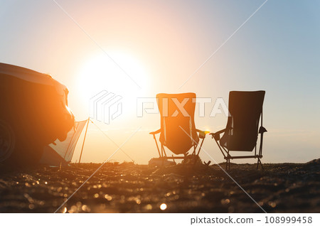 Two empty picnic chairs, next to a car, outdoors. place for camping and weekend getaway 108999458
