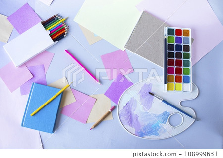 Back to school, watercolor paints, brushes and colored pencils, palette, school supplies on a gray background, top view  108999631