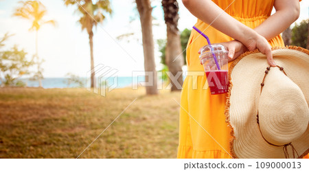 a woman in a summer hat relishes pomegranate juice 109000013