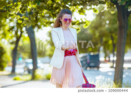 happy woman in dress and jacket in city walking 109000444