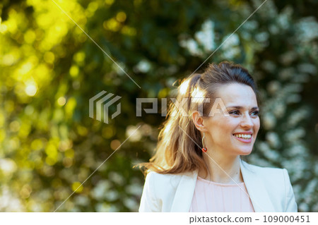 happy modern female in pink dress and white jacket in city happy modern female in pink dress and white jacket in city 109000451