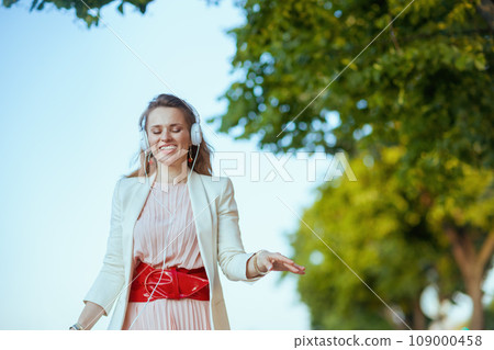 smiling trendy woman in city listening to music 109000458