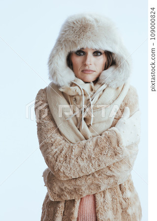 sad modern woman in winter coat and fur hat shivering on white 109000824
