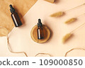 Hand making DIY scene. Glass amber bottles with black cap flat lay. Beauty products packaging. Dropper bottle with pipette on wooden podium. Natural eco-friendly cosmetics presentation with copy space 109000850