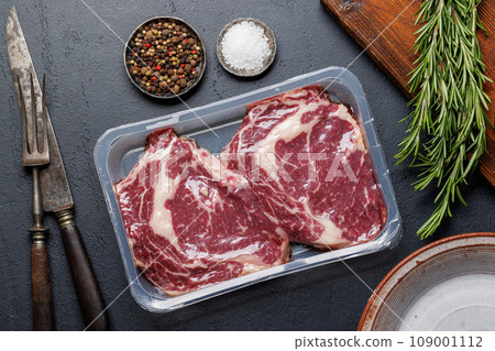 Raw ribeye steaks with savory spices 109001112