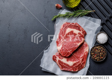 Raw ribeye steaks with savory spices 109001115