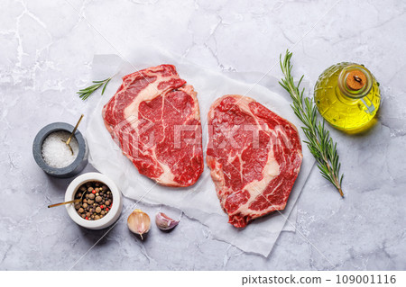 Raw ribeye steaks with savory spices 109001116