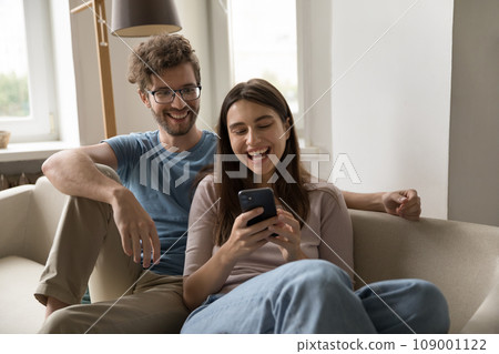 Pretty girl showing videos on cellphone to joyful boyfriend 109001122