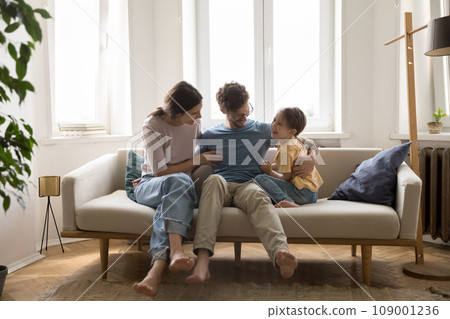 Smiling family spend time together at home sit on sofa 109001236