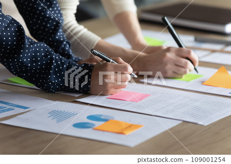 Hands of coworker women writing notes on paper stickers 109001254