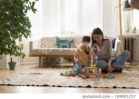 Mother with daughter spend time playing on floor with blocks 109001257