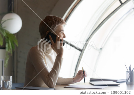 Happy business woman making telephone call from office workplace 109001302