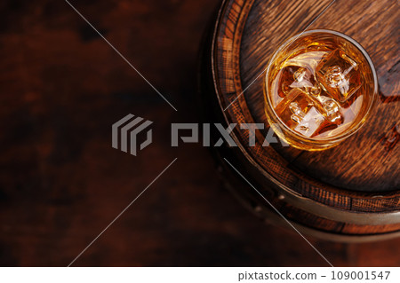 Whiskey glass with ice on a rustic barrel, a classic sip 109001547
