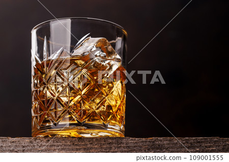 Whiskey glass with ice on a rustic barrel, a classic sip 109001555