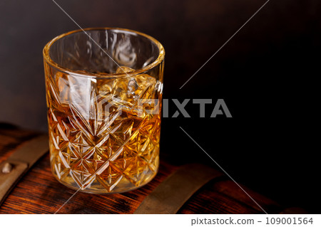 Whiskey glass with ice on a rustic barrel, a classic sip 109001564