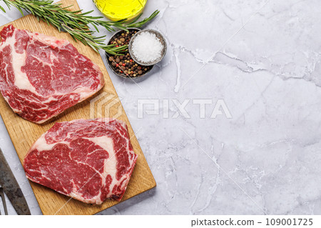 Raw ribeye steaks with savory spices 109001725