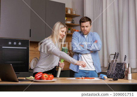 Leave Me Alone. A woman is preparing food, and a man is talking to her, and is not satisfied with the way she is cooking. Leave Me Alone. A woman is preparing food, and a man is talking to her, and is not satisfied with the way she is cooking. 109001751